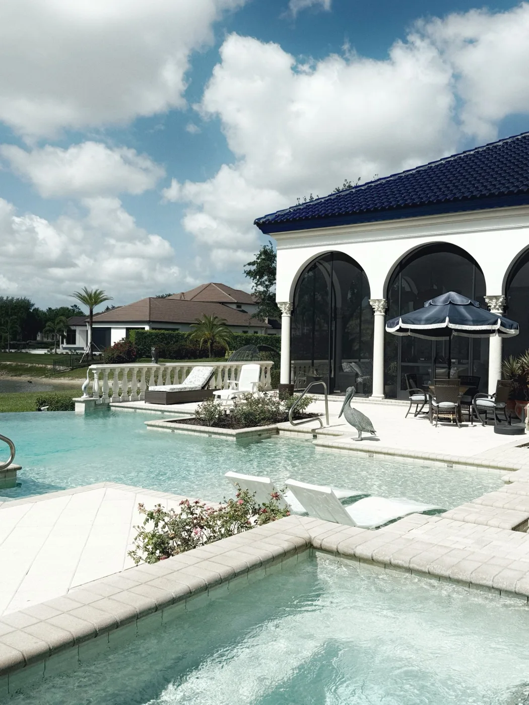 Estate swimming pool and spa beside a screened lanai, with outdoor seating and landscaped grounds