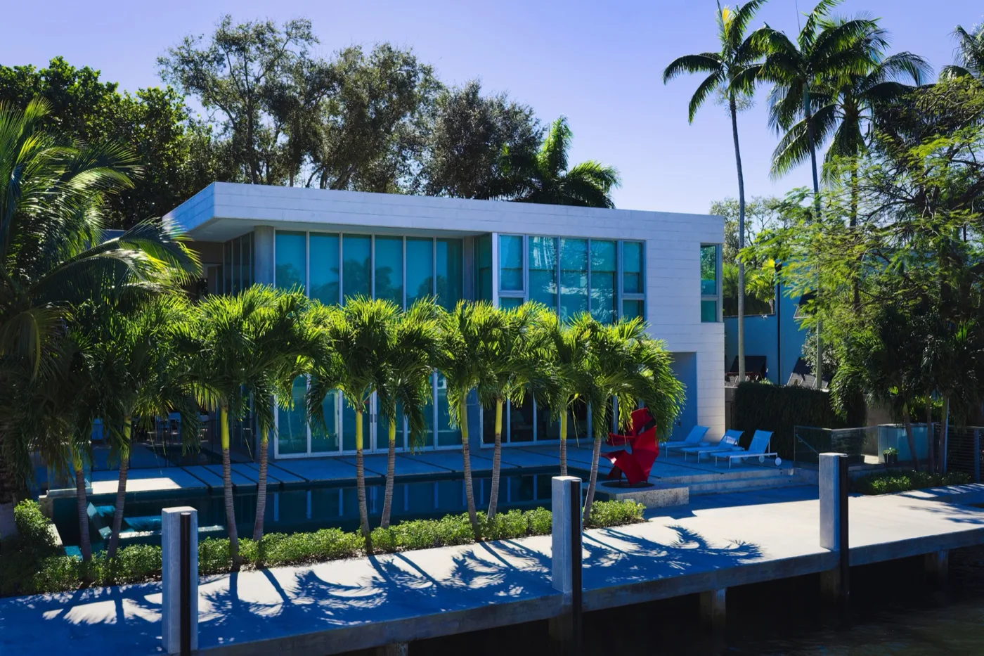 Modern waterfront estate with glass walls, palm landscaping, a swimming pool and a private dock
